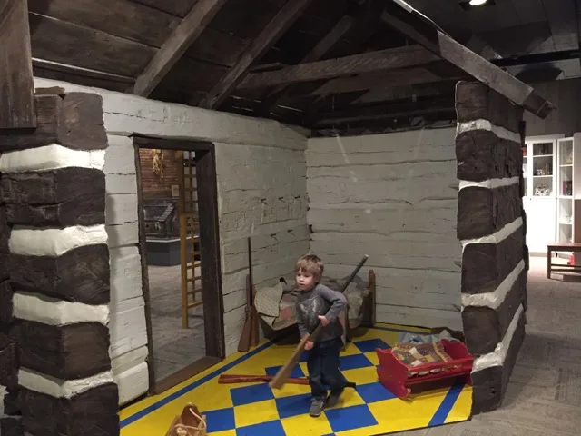 boy playing in the log cabin area at Ohio History Center
