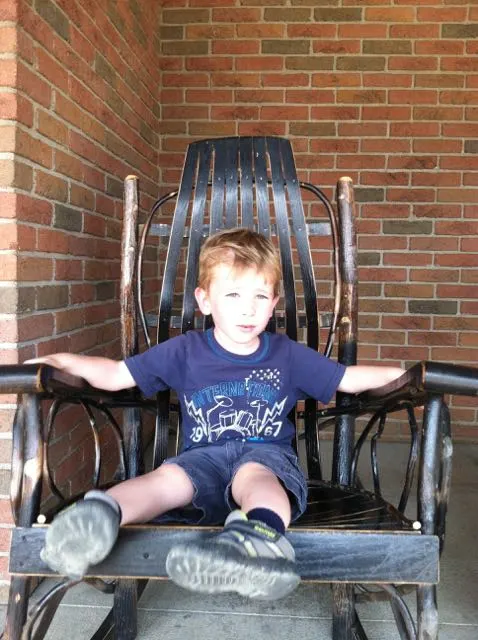 boy sitting on a rocking chair outside Der Dutchman