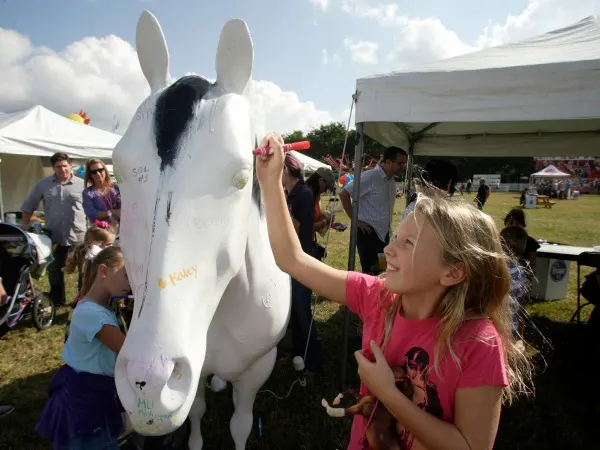 Carys Wasil, 10, of Blacklick signs the Ohio State University Equine Department's horse statue during the New Albany Classic Sunday, Sept. 21, 2014.