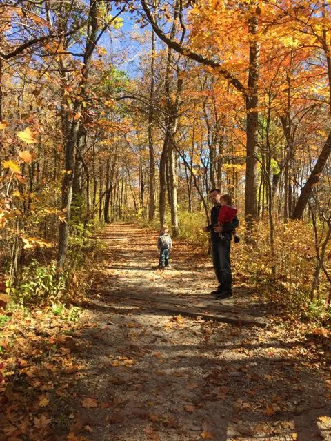 Family walking on a path at a metro park in columbus, Ohio with fall foliage.