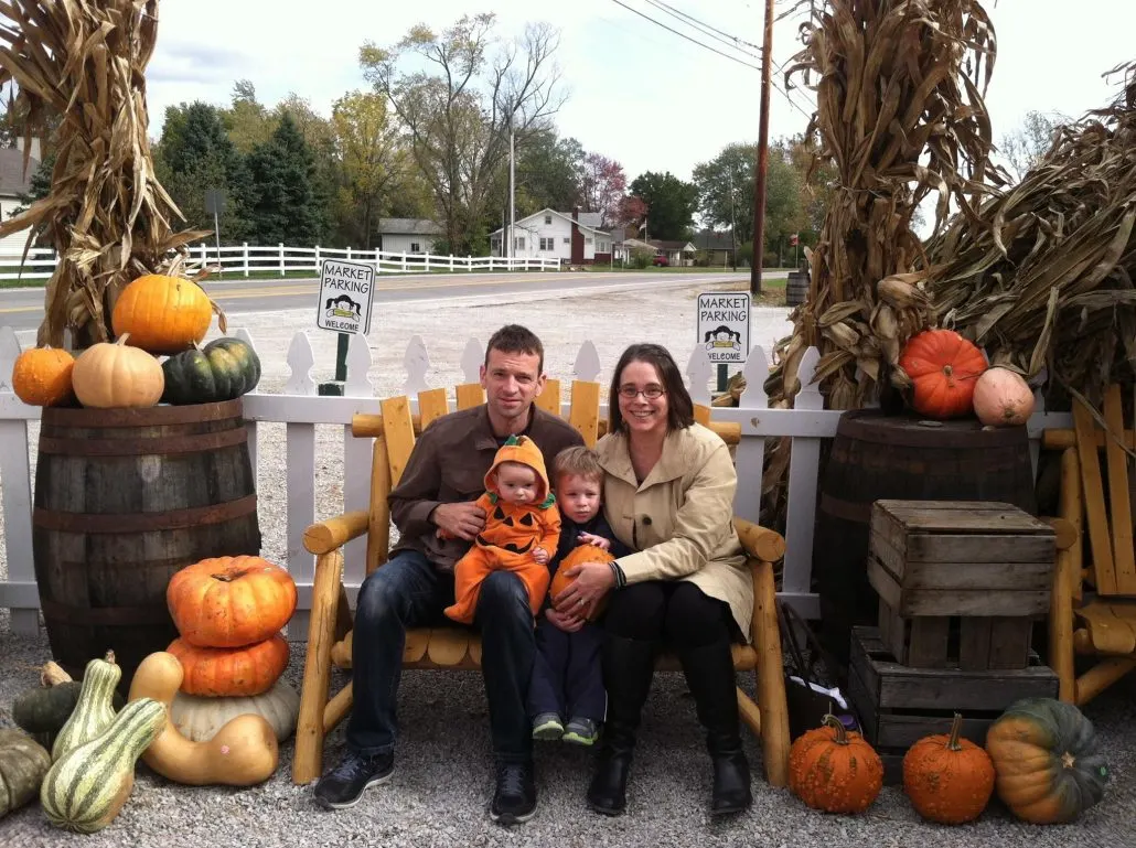 Family sitting on a bench amidst pumpkins at Smith Farm Market in Columbus, Ohio.