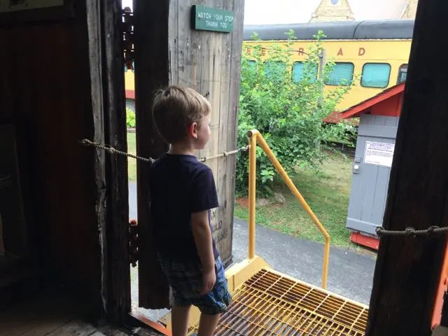 boy looking out the door of the train car