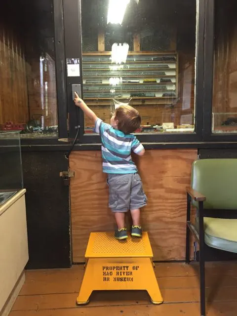 boy pressing the button to make the train go at the NKP Railroad Museum