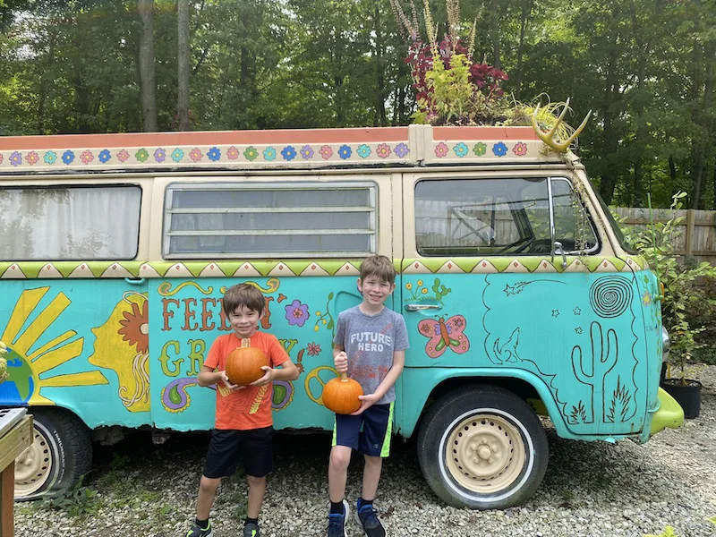 Two boys holding pumpkins in front of the VW Bus at Groovy Plants Ranch