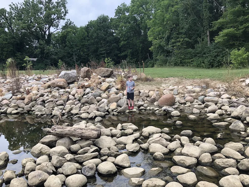 boy walking on the rocks in the creek