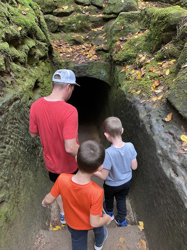 man and two boys heading into a cave tunnel in Hocking Hills
