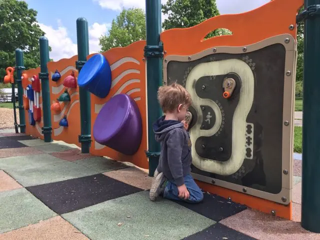 little boy playing on a wall of toddler activities at Friendship Park in Gahanna, Ohio.