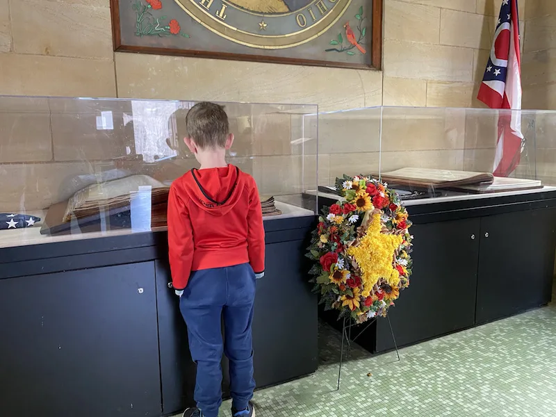 boy looking at the books under glass at the Ohio Memorial Forest Shrine.