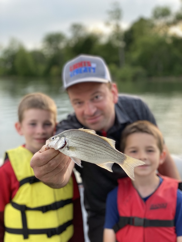 two boys and father with a fish.