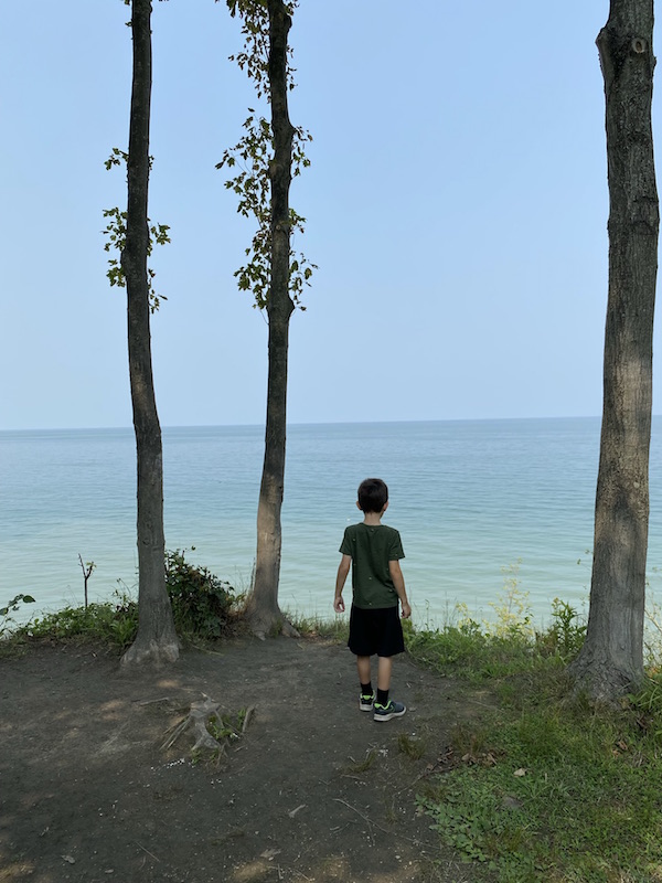 A boy overlooking Lake Erie from a cliff above.