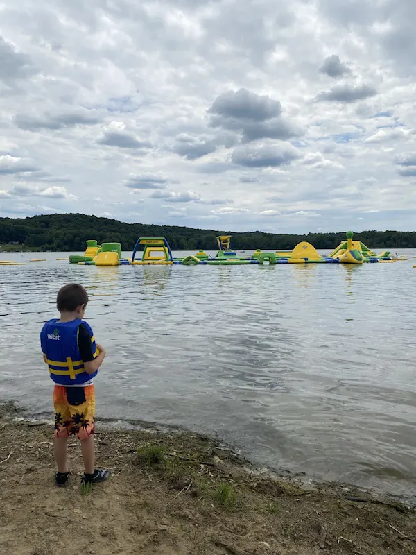 boy standing on the beach in front of the Whoa Zone at Pleasant Hill Lake.