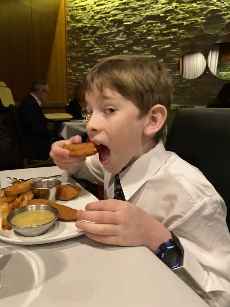 Boy eating a chicken finger at Mitchell's Ocean Club, a restaurant in Columbus, Ohio.