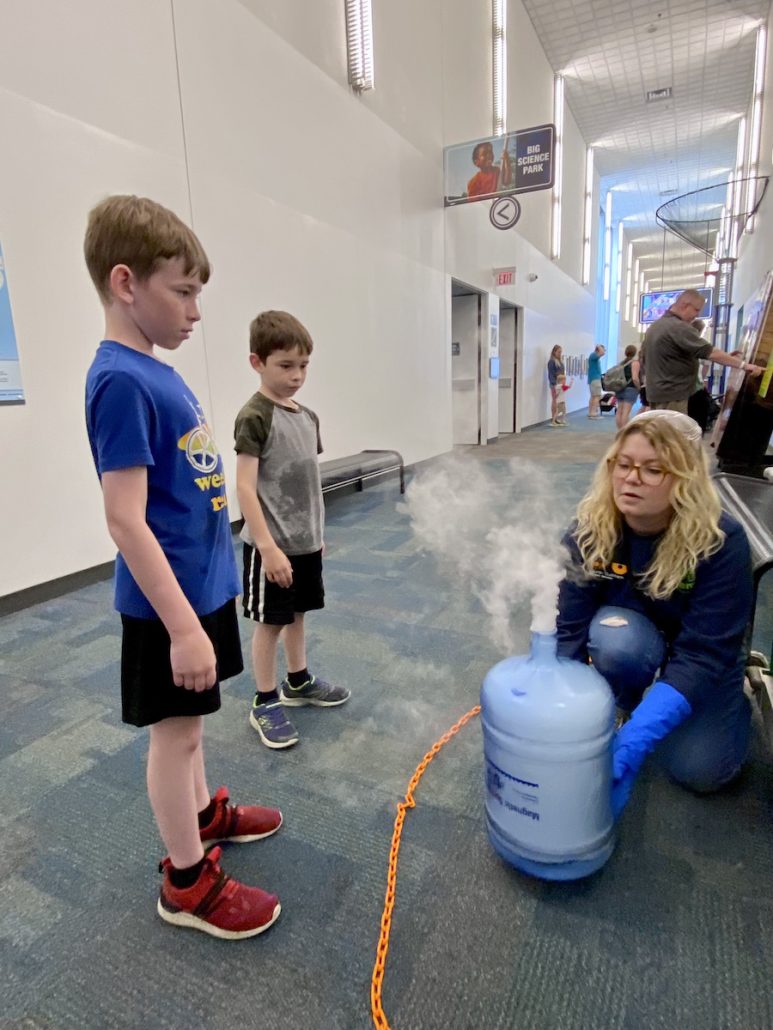 Two boys watching a science experiment with dry ice in the hallway at COSI in Columbus, ohio.