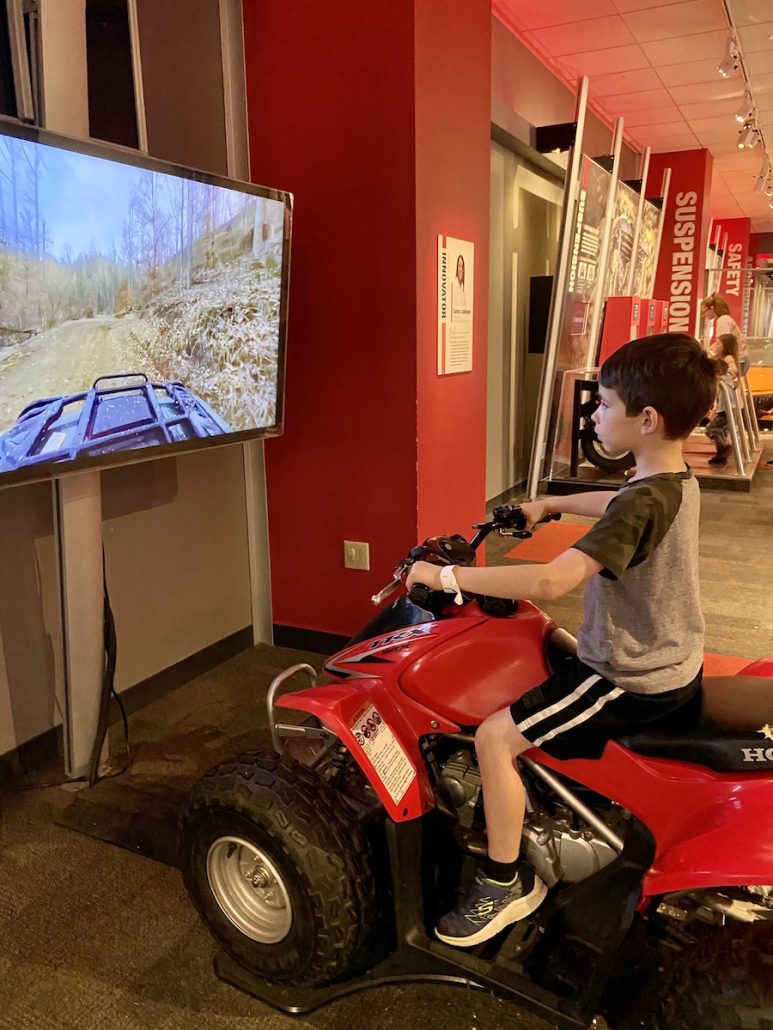 Boy riding a stationary dirt bike at the Innovators exhibit at COSI.