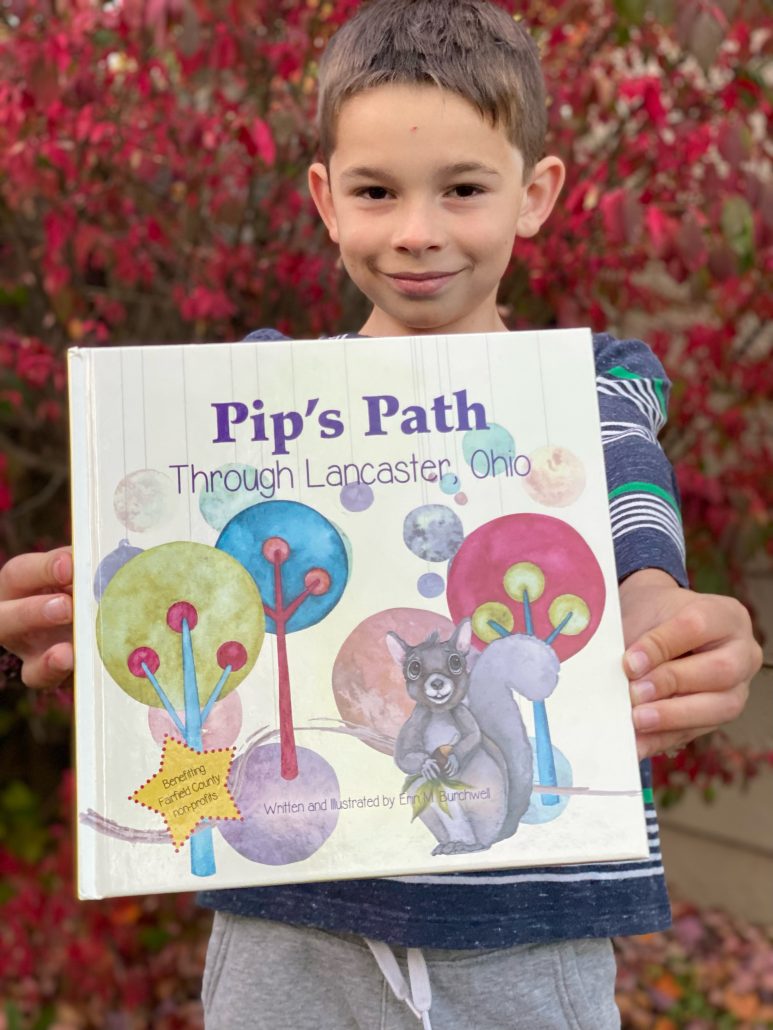 Boy holding the book Pip's Path Through Lancaster, Ohio.