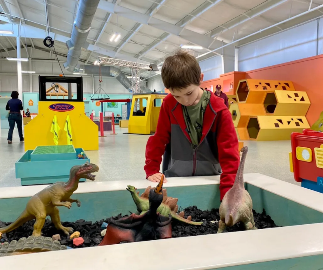 A boy playing with toy dinosaurs at the A-HA Children's Museum in Lancaster, Ohio.