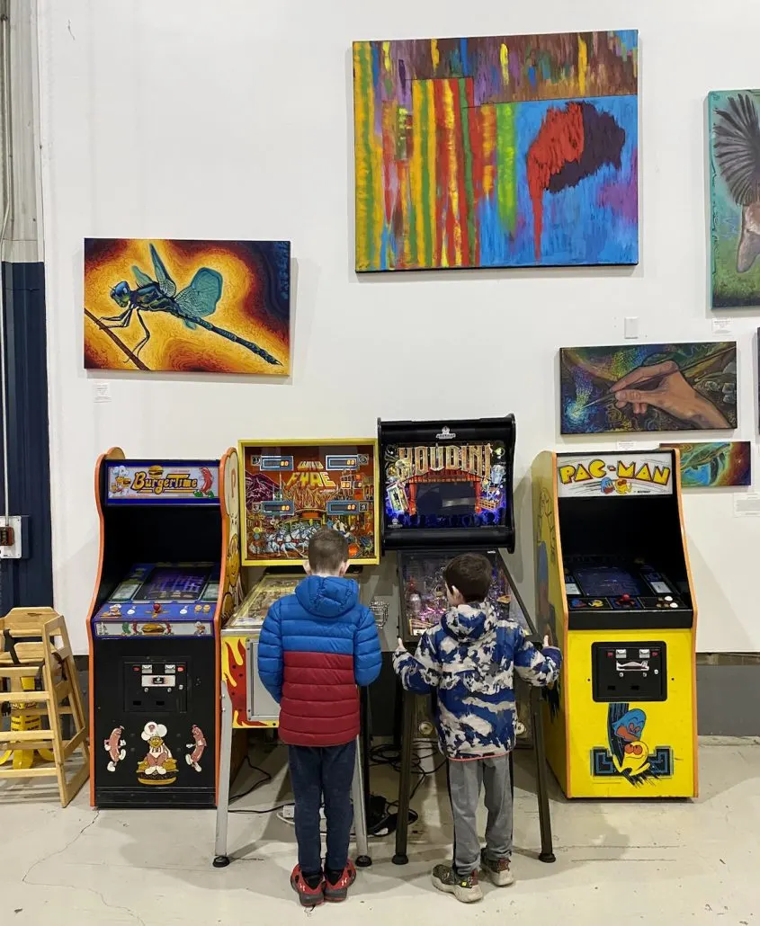 Two boys playing arcade games inside Logan Street Market, a kid-friendly place to eat in Louisville.