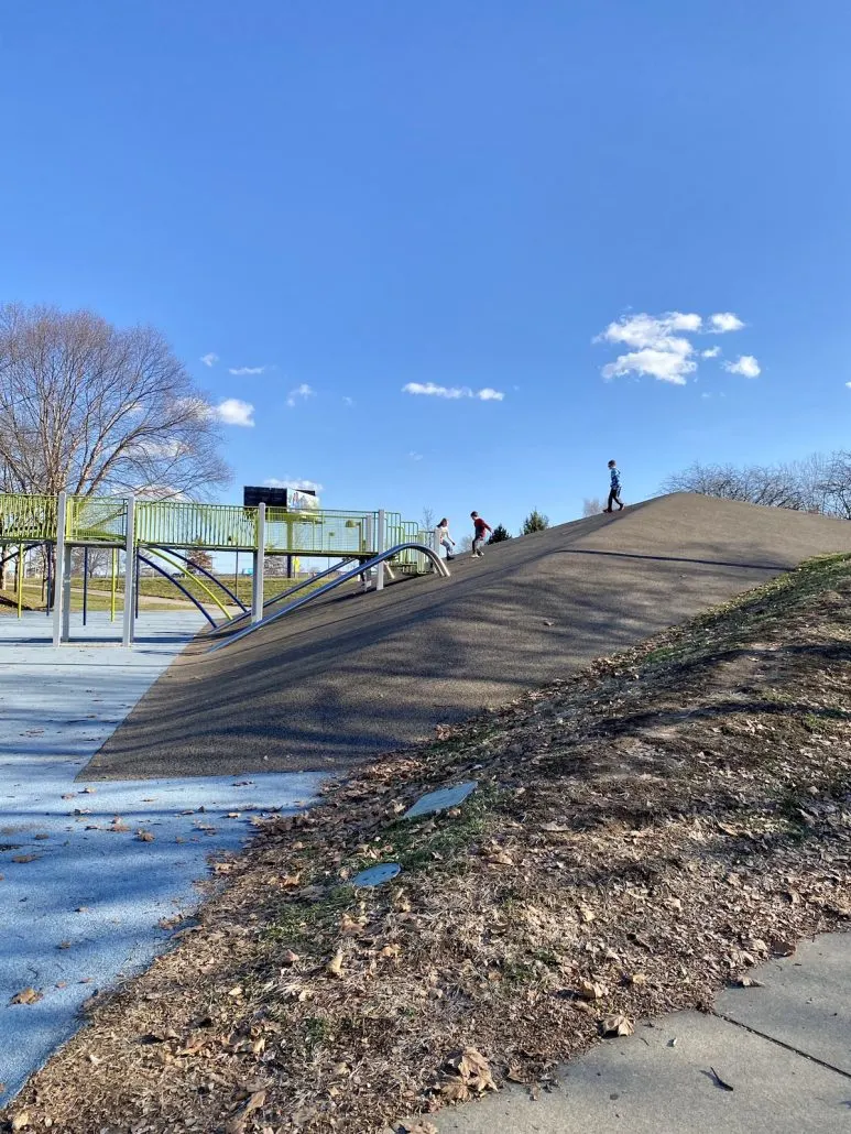 Kids playing on a steep hill at the Adventure Playground at Waterfront Park in Louisville, KY.