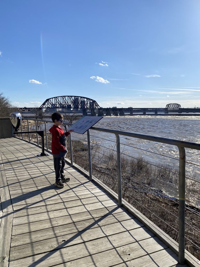 A boy reading an informational sign at the Falls of Ohio State Park overlooking the Ohio River.