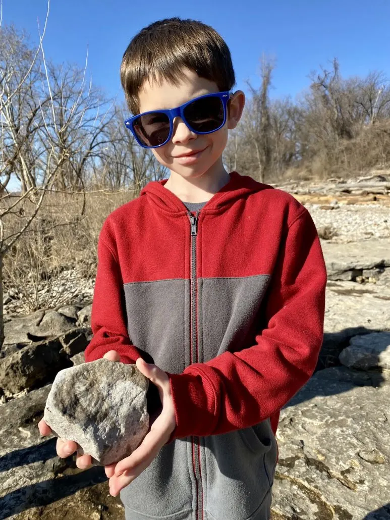 A boy holding a fossil in a rock at the Falls of Ohio State Park.