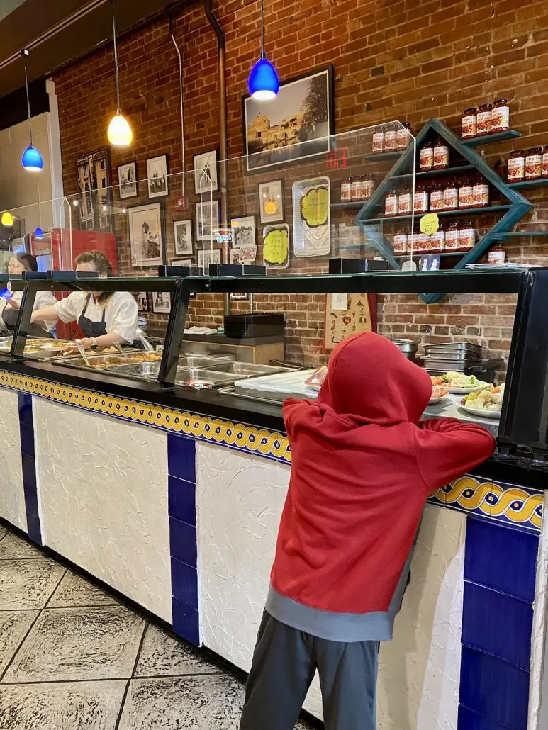 A boy standing at the counter to order food at Luigi's Pizza in downtown Louisville, Kentucky.
