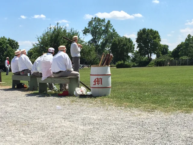 Men sitting on a bench to play base ball for the Ohio Village Muffins at a historical village in Columbus, Ohio.