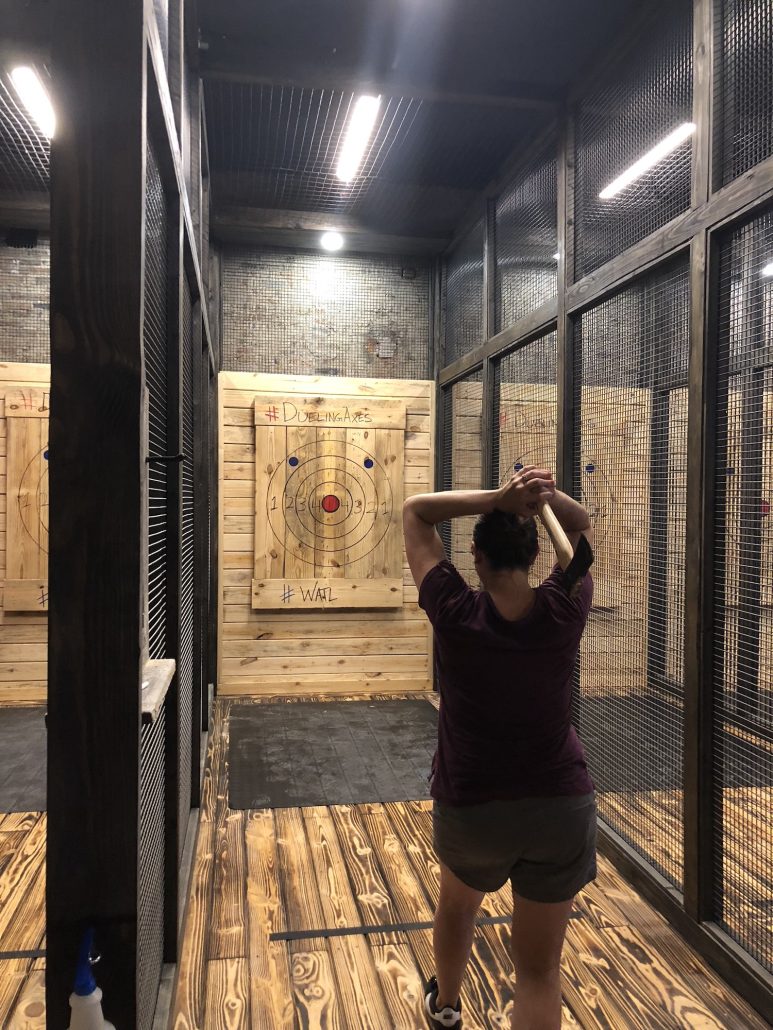 A woman throwing an axe at Dueling Axes, a fun date idea in downtown Columbus, Ohio.