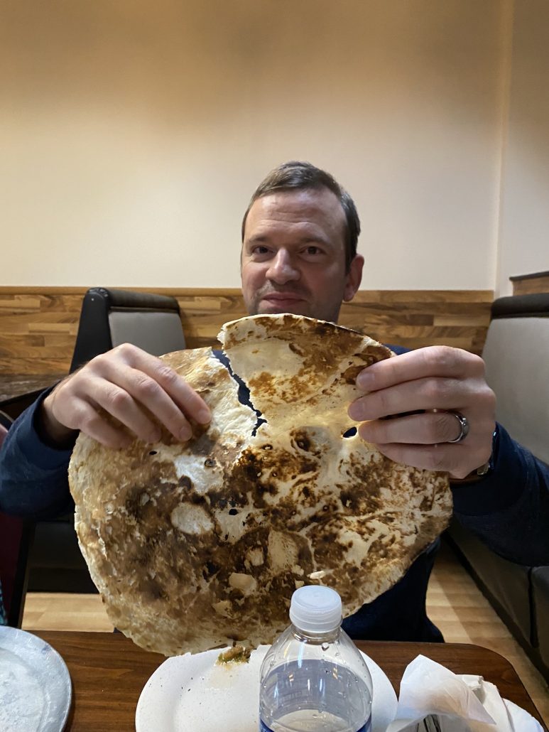 A man holding a large pita bread at a restaurant on a Columbus Food Adventures tour, a great date idea in Columbus.