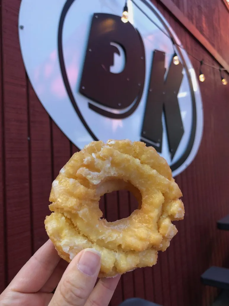 A sour cream donut held up in front o the DK sign at DK Diner in Grandview Heights.