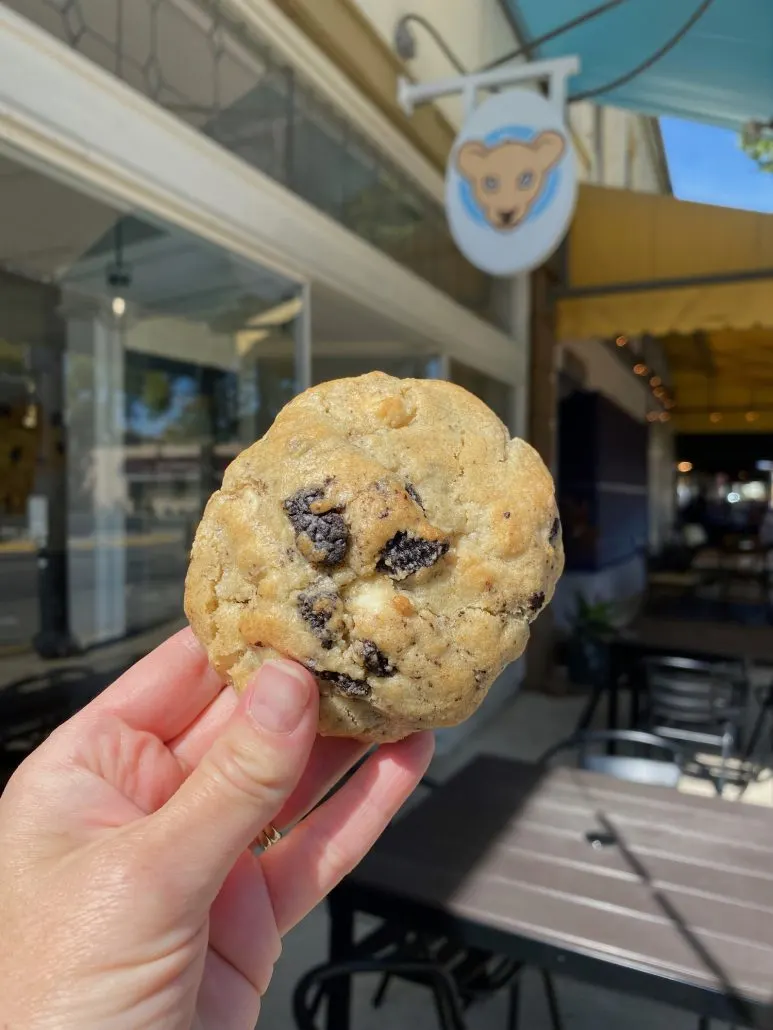 A chocolate chip cookie held up in front of Lion Cub's Cookies in Grandview.