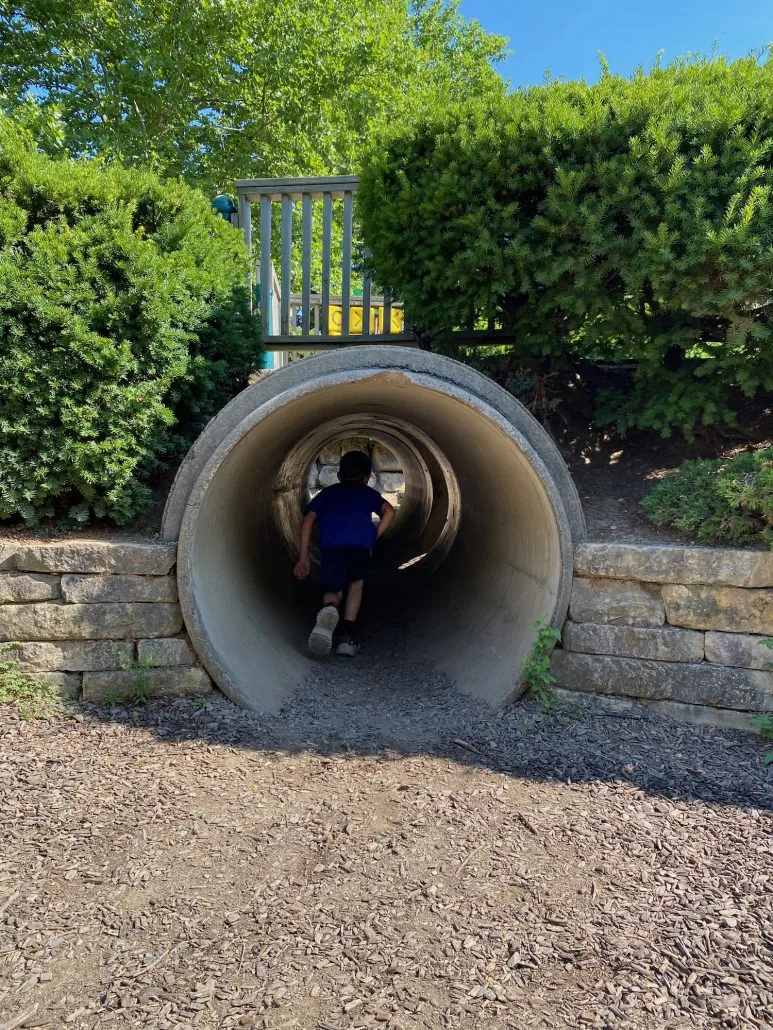 A boy running through a tunnel in the playground.