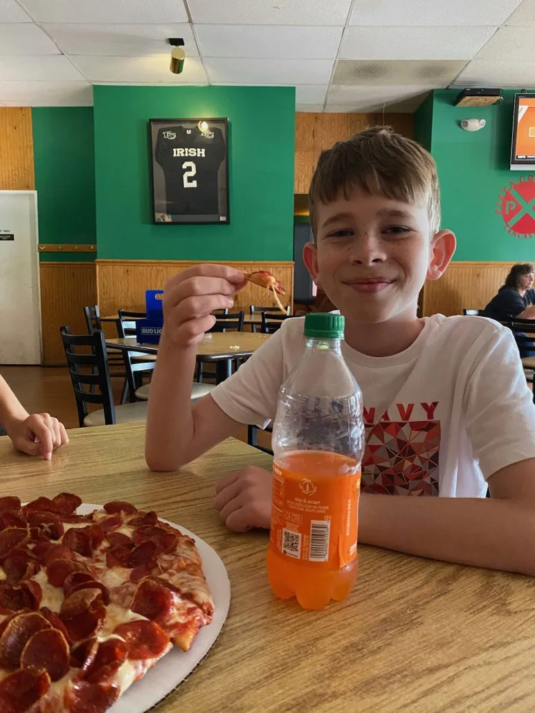 Boy eating a piece of pizza at Pizza Crossing in Lancaster.