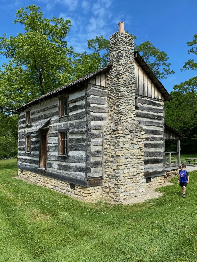 A boy standing in front of the Log House at Indian Mound Reserve in Greene County, Ohio.
