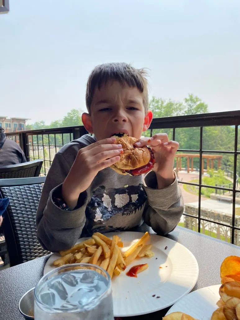 Boy eating a hamburger on the patio of Rock House Restaurant in Hocking Hills, Ohio.