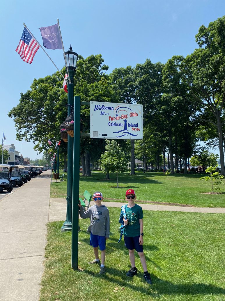 Two boys in front of the Welcome to Put-in-Bay, Ohio sign.