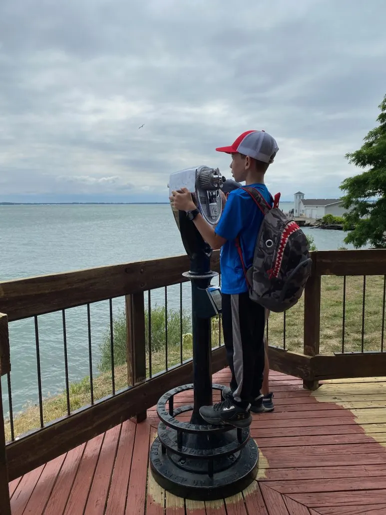 A boy looking through a viewfinder at Lake Erie.