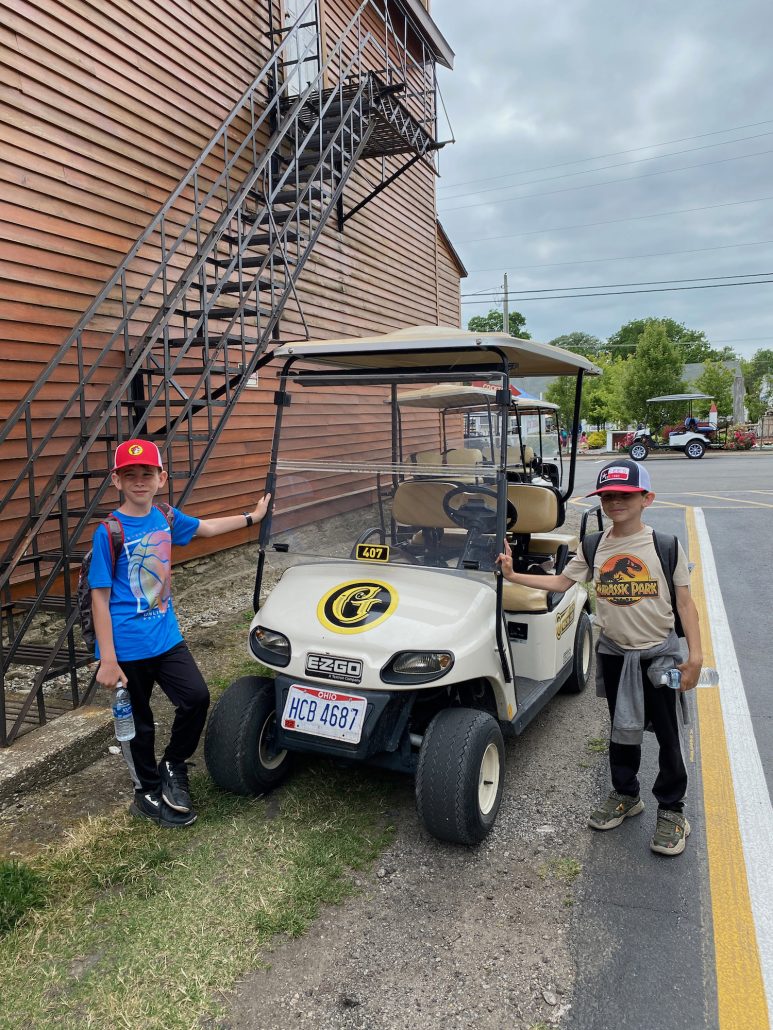Two boys standing by a golf cart at the General Store.