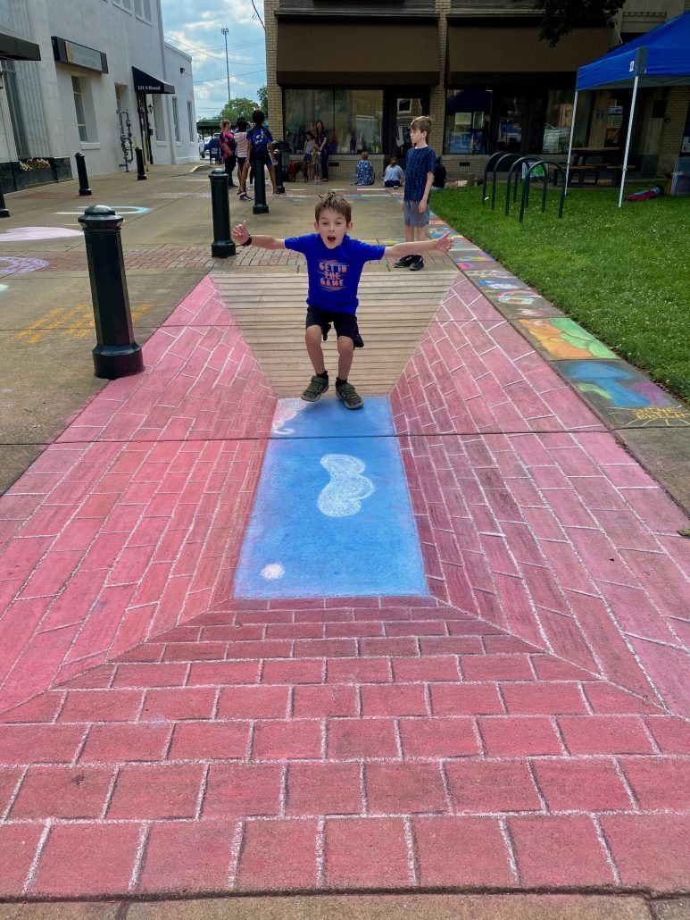 Boy interacting with chalk drawings on Zane Square during the Lancaster Festival.