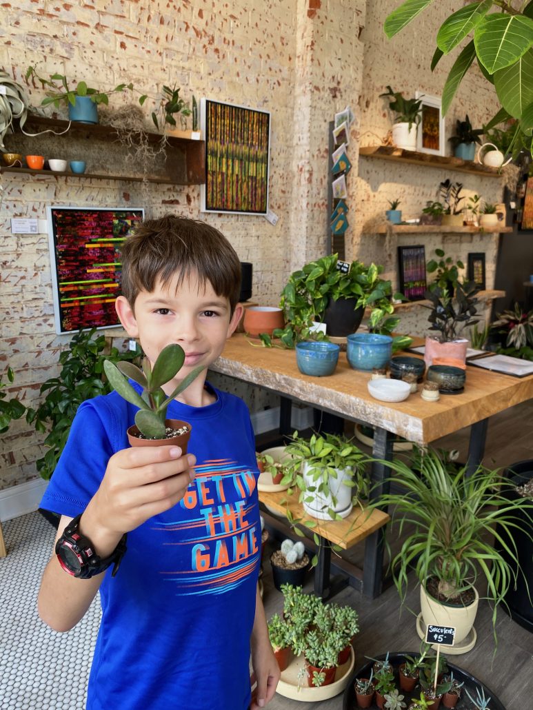 A boy holding a plant inside STUMP: Lancaster.