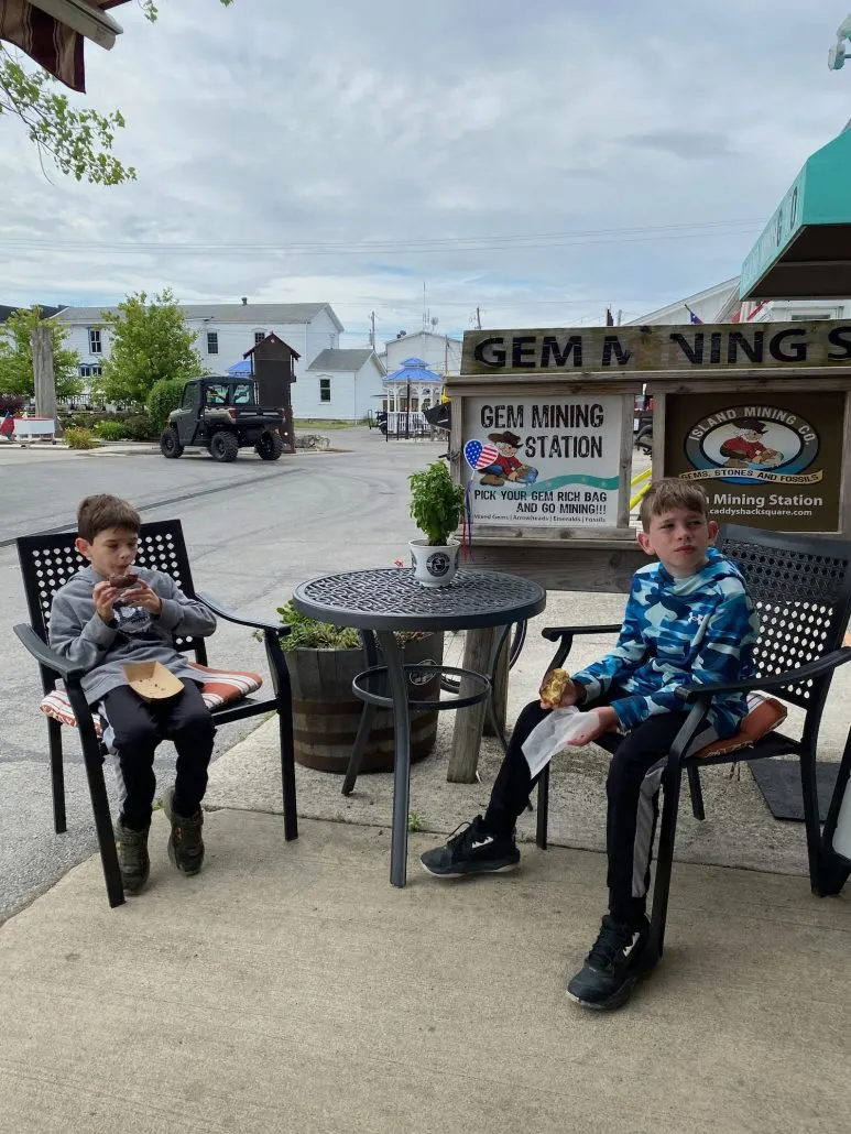 Two boys eating donuts at a picnic table in Caddy Shack Square.