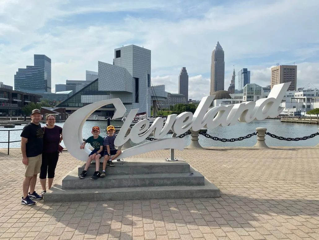 A family standing in front of the Cleveland Script sign at North Coast Harbor.