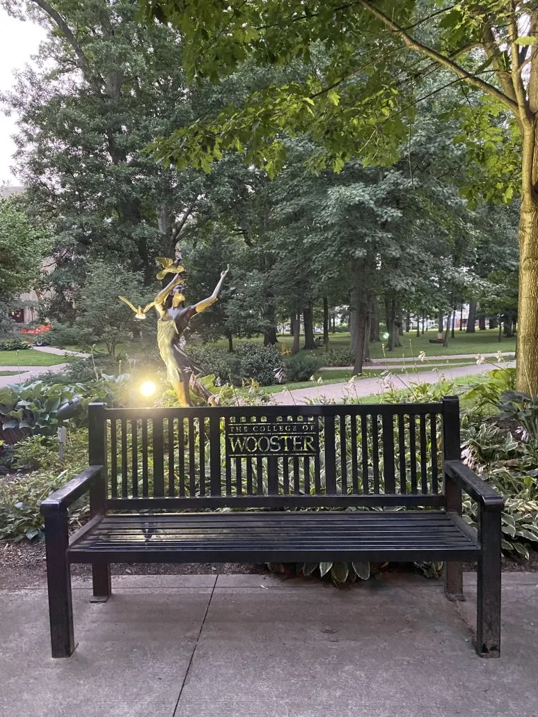A bench and statue at The College of Wooster.