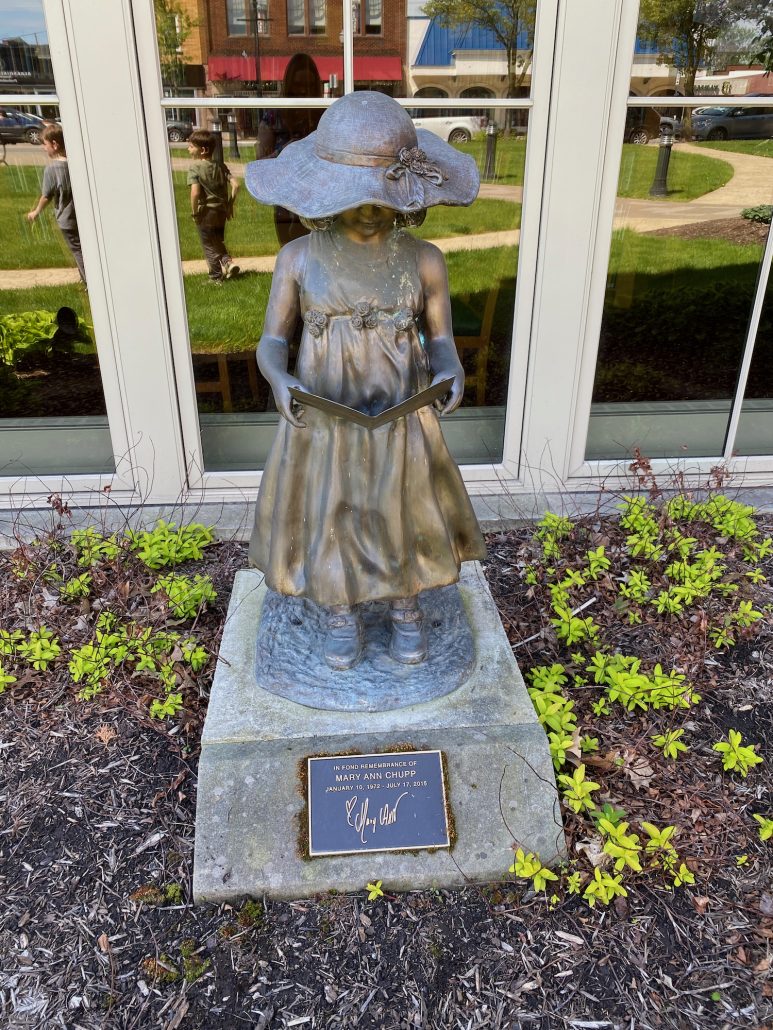 A statue called Charlotte - Southern Girl Reading in front of the Wayne County Public Library.