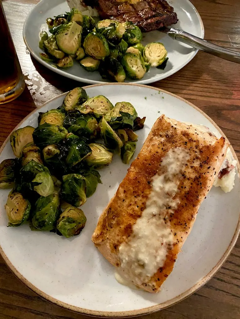 Dinner plates at 58 West featuring steak and salmon with brussels sprouts.