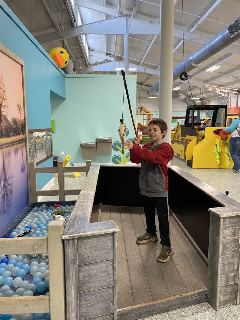 A boy catching a pretend fish at the A-HA Children's Museum in Lancaster, Ohio.