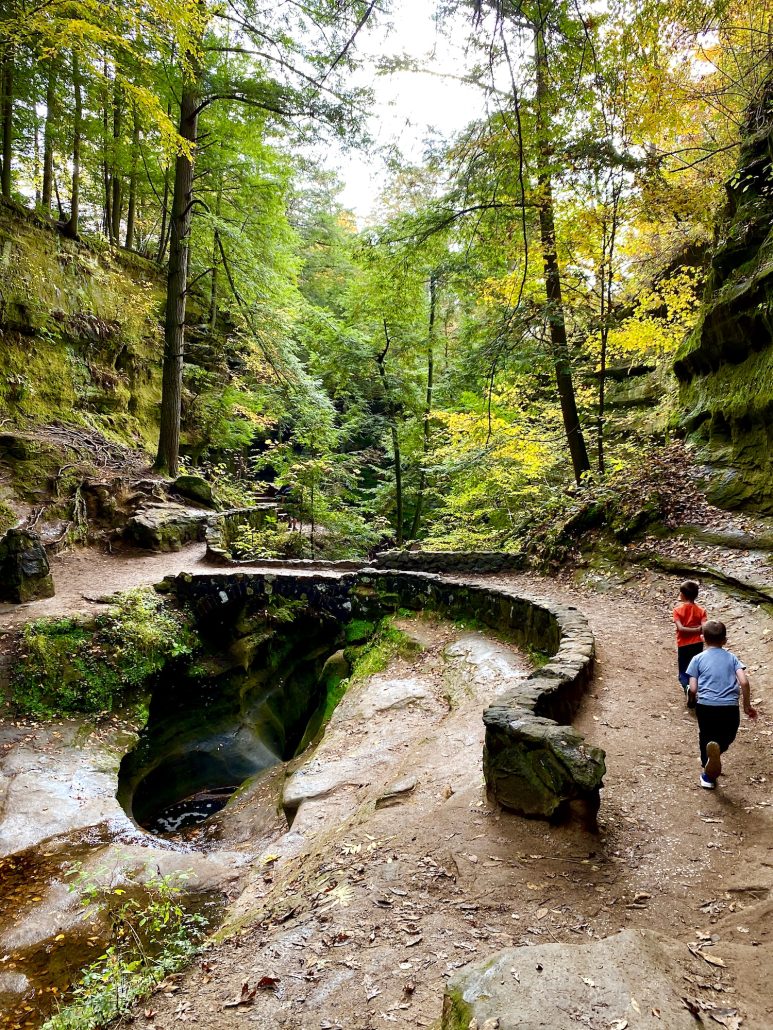 Two boys running on a path at Hocking Hills State Park in the fall.
