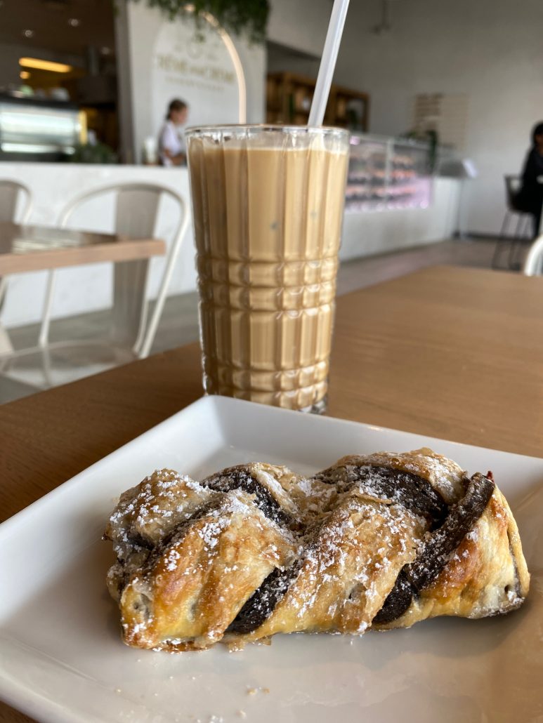 An iced latte and chocolate pastry sitting on a table.