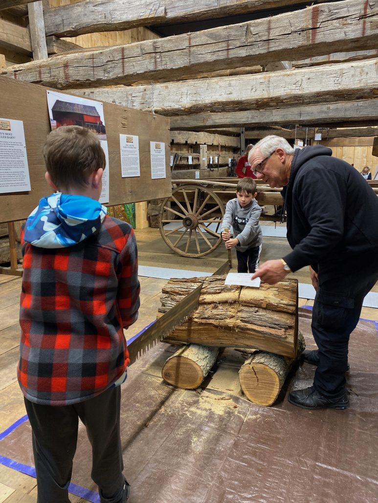 Two boys learning how to use an old fashioned saw at Buckeye Agricultural Museum.