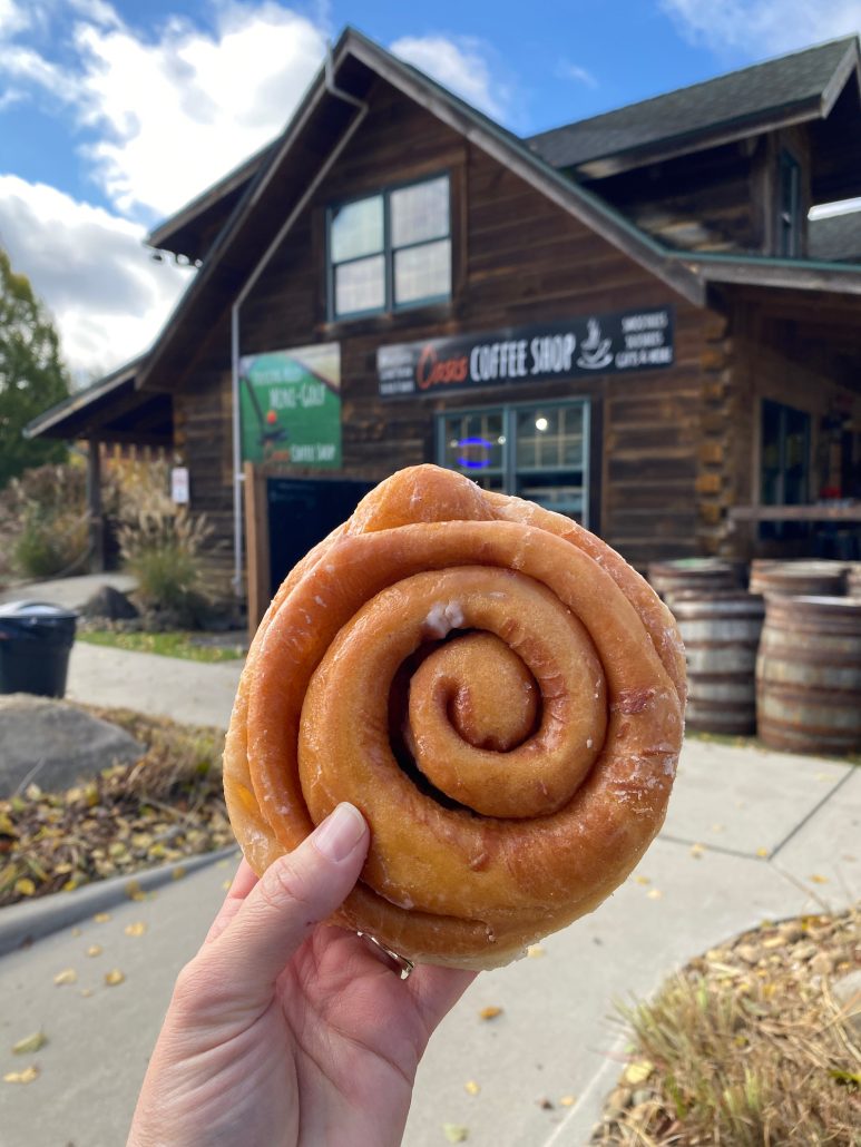 A large cinnamon roll held up in feont of Oasis Coffee Shop in Hocking Hills.