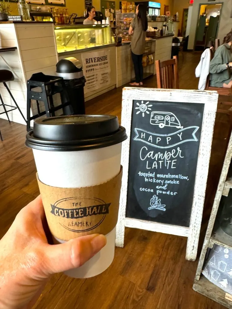 Coffee Cup and sign advertising the Happy Camper Latte at Coffee Hall and Creamery, a coffeeshop in Marysville, Ohio.